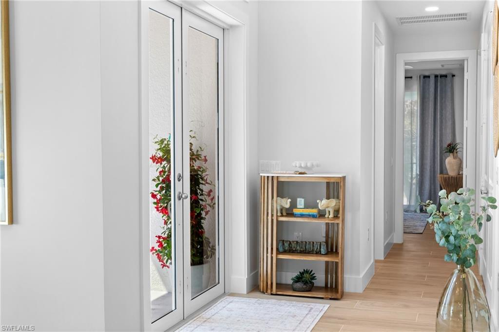 Entryway with French doors featuring textured glass, leading to an outdoor area with vibrant red foliage