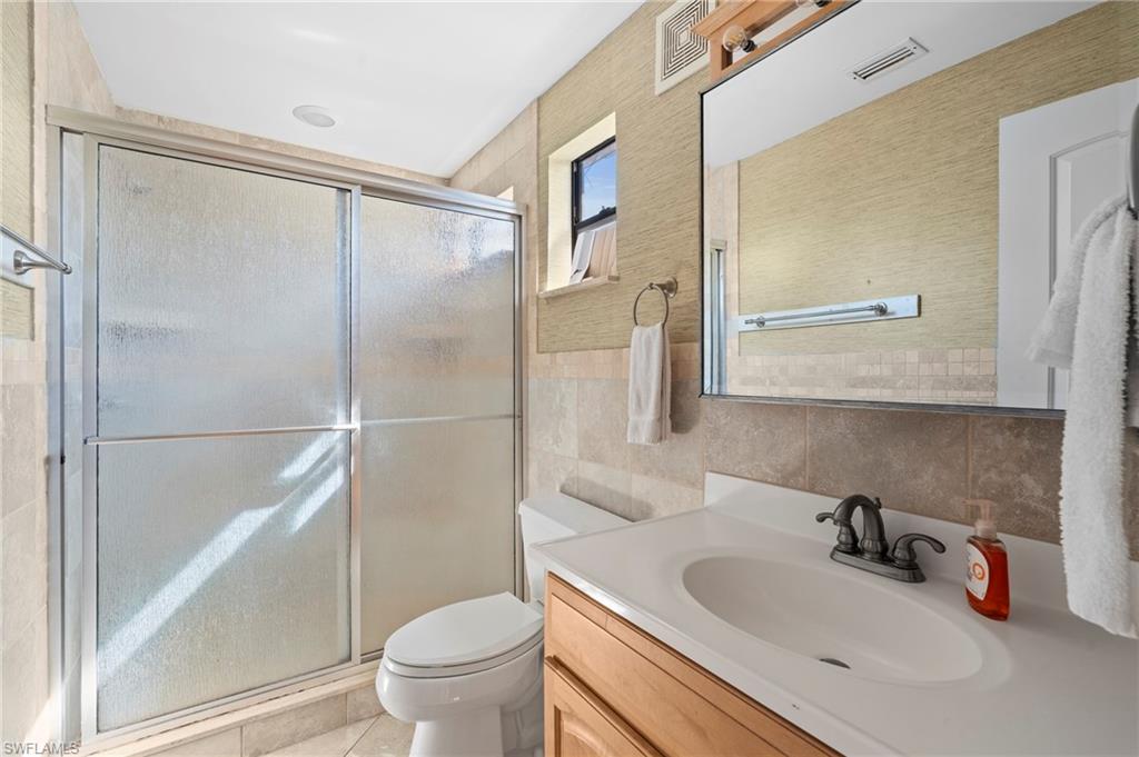 Bathroom featuring a spacious glass-enclosed shower and a vanity - Virtually Edited Image