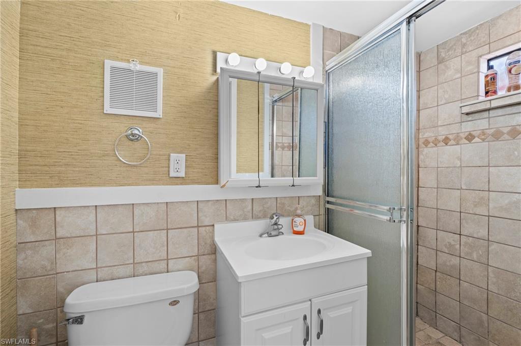 Bathroom with tiled shower, vanity storage, and a mirrored cabinet - Virtually Edited Image