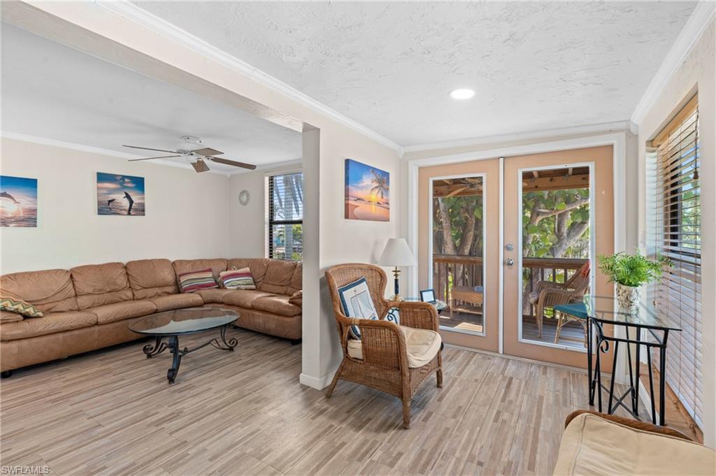 Cozy, sunlit living room with beachy decor and access to a private deck - Virtually Edited Image
