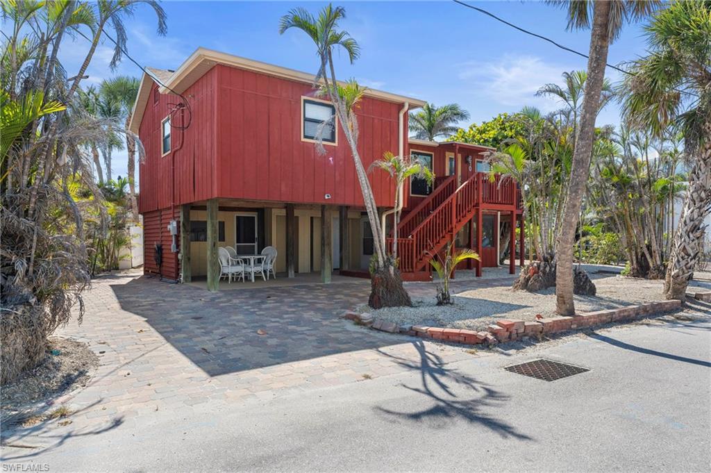 Two-story beach house featuring a wraparound staircase, and patio area—ideal for relaxing in a tropical paradise - Virtually Edited Exterior Image
