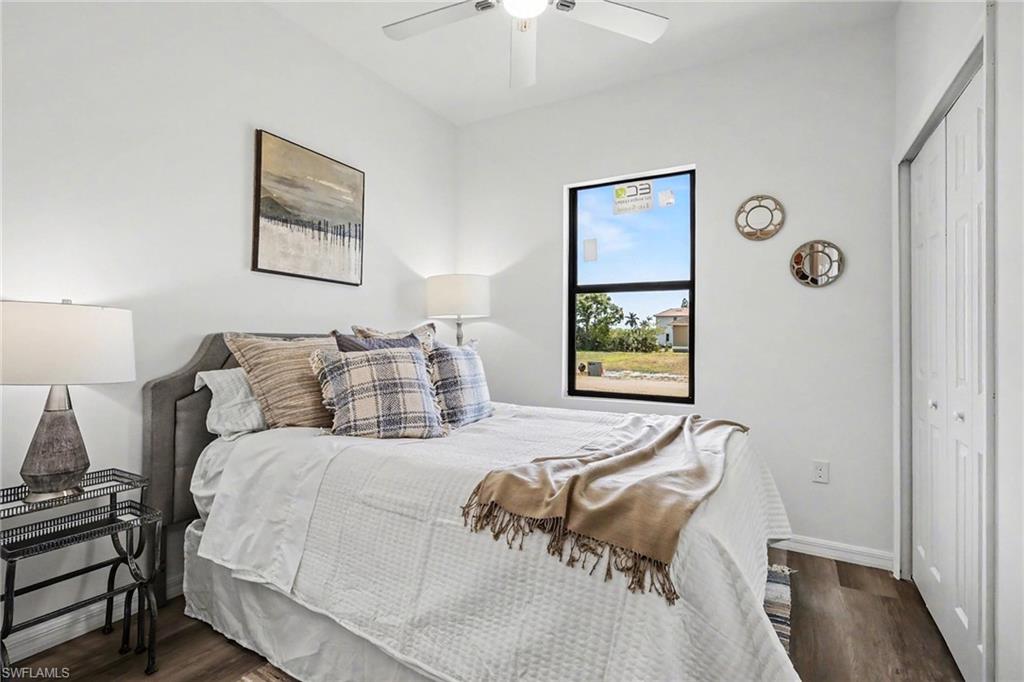 Bedroom featuring wood-finish flooring, a contemporary ceiling fan, and a single black-framed window