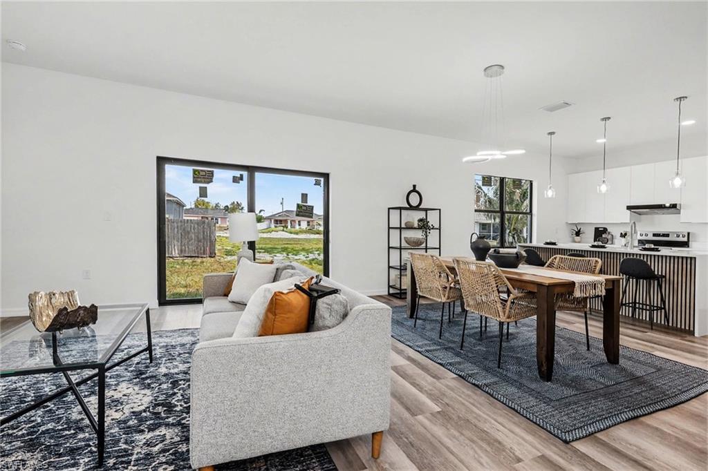 Open-concept living space featuring wood-finish flooring, recessed lighting, and a large dining area with modern pendant lights