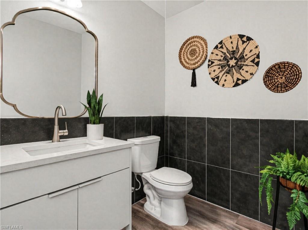 White vanity with integrated sink, brushed nickel faucet, and a scalloped mirror added virtually