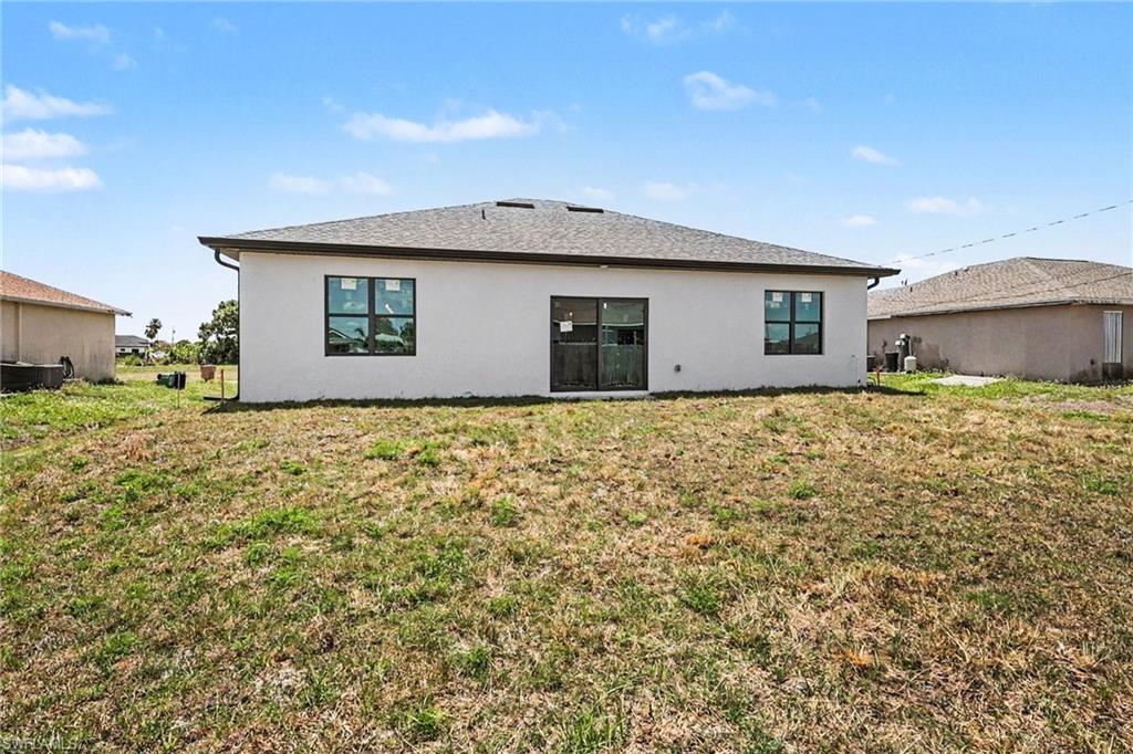 Rear exterior featuring a white stucco finish, dark-framed windows, and sliding glass doors