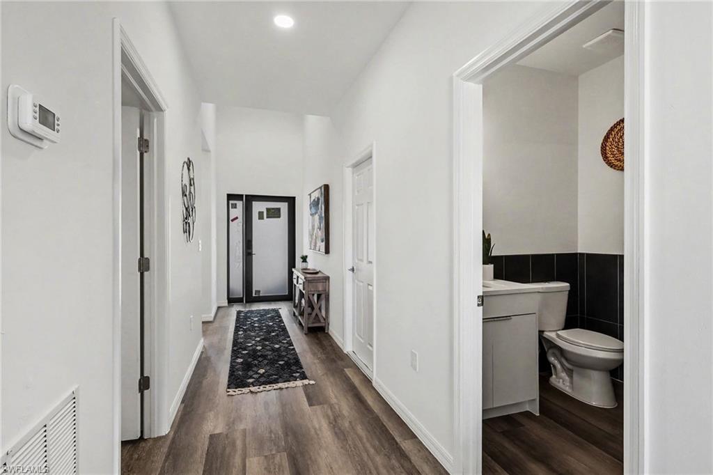 Hallway featuring wood-finish flooring, recessed lighting, and a modern thermostat