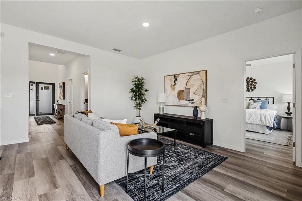 Spacious living area featuring wood-finish flooring, recessed lighting, and a neutral color palette