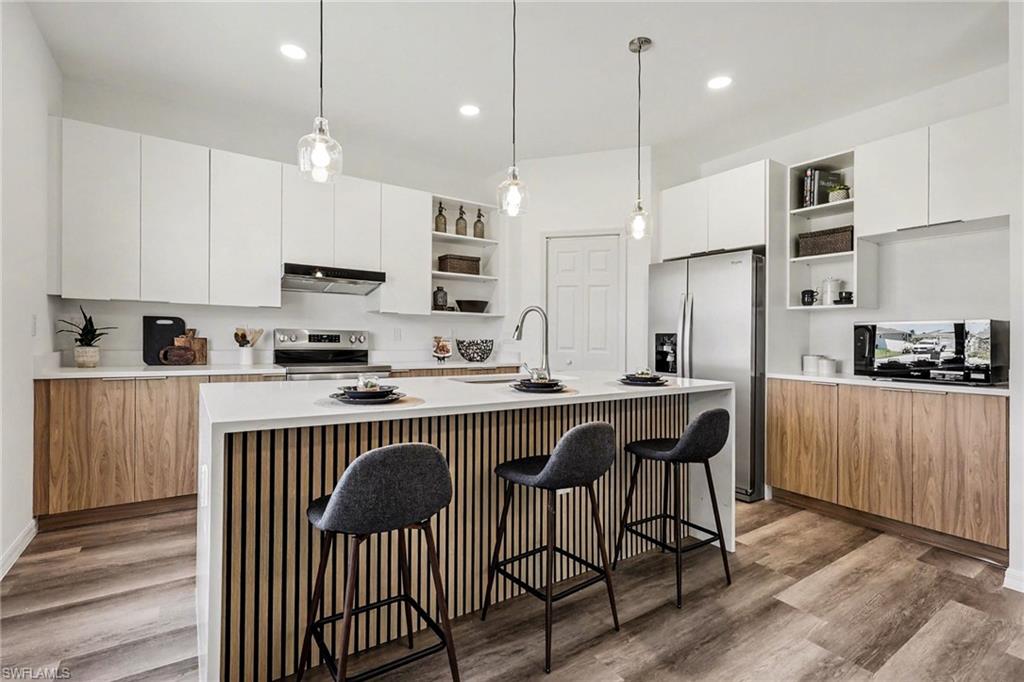 Modern kitchen featuring a waterfall island with slatted wood-finish paneling, white countertops, and wood-finish lower cabinetry