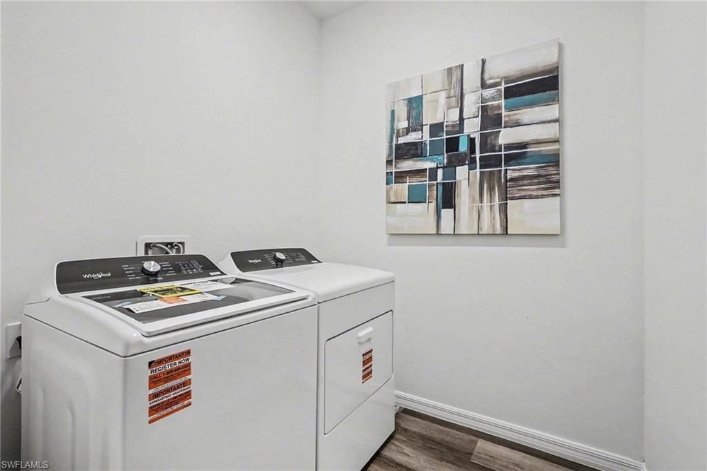 Dedicated laundry area featuring light-toned walls, wood-finish flooring, and white baseboards