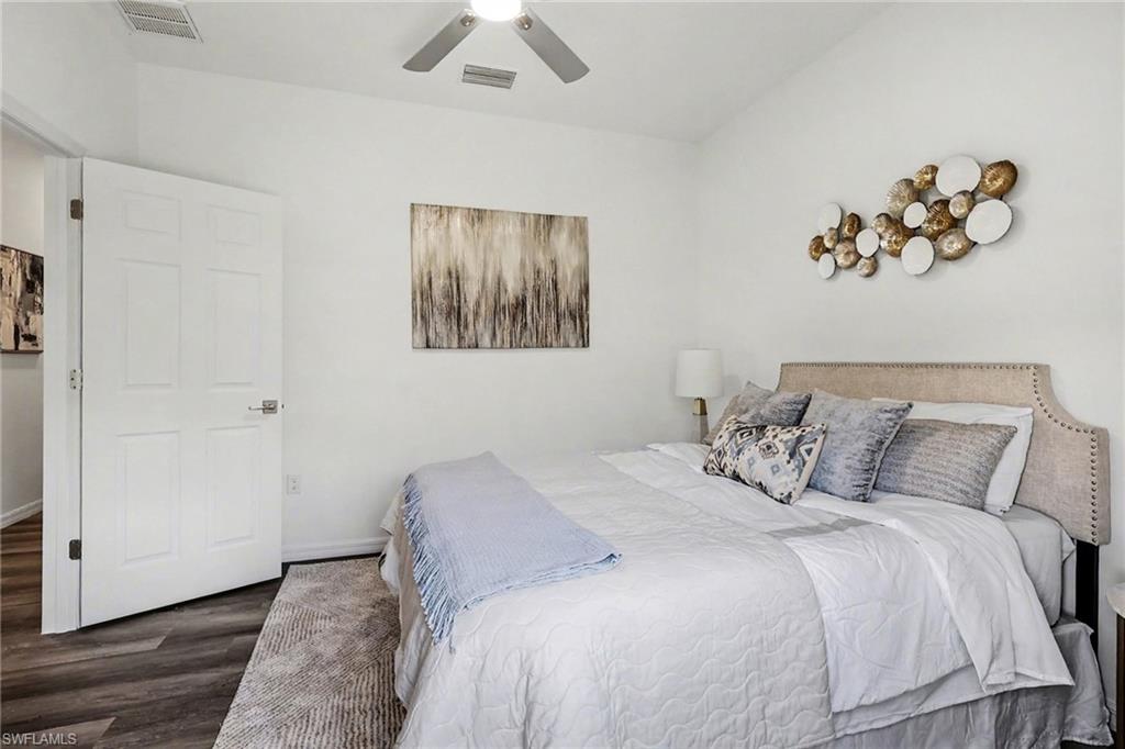 Bedroom featuring wood-finish flooring, white walls, and a ceiling fan