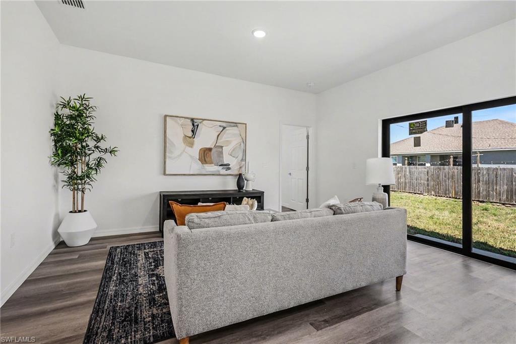 Open concept living area featuring contemporary light wood-finish flooring and bright white walls