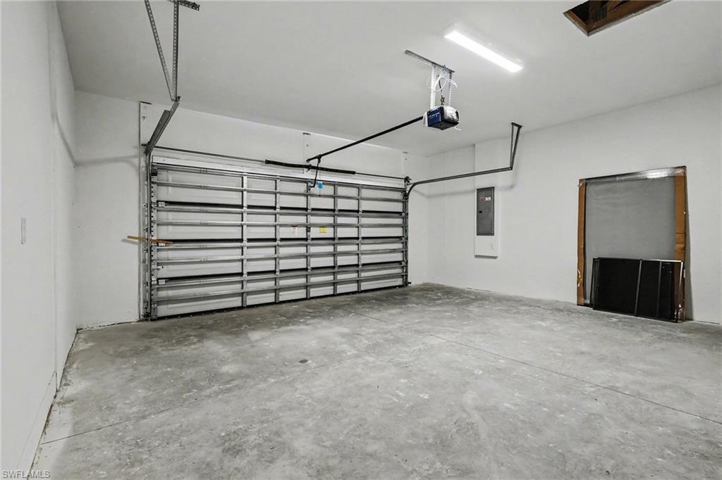 Spacious garage featuring a concrete floor, white walls, and a large overhead door