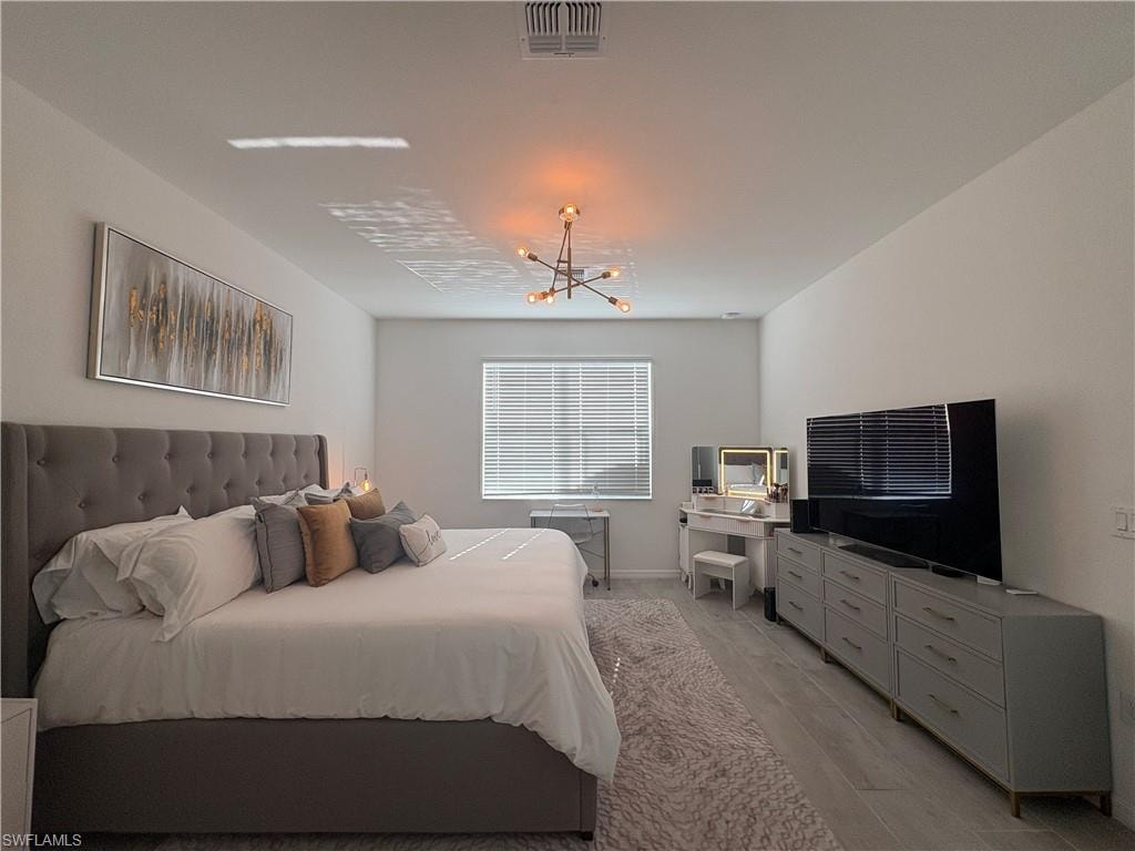 Spacious room featuring light-toned wood-finish flooring and a central ceiling light fixture