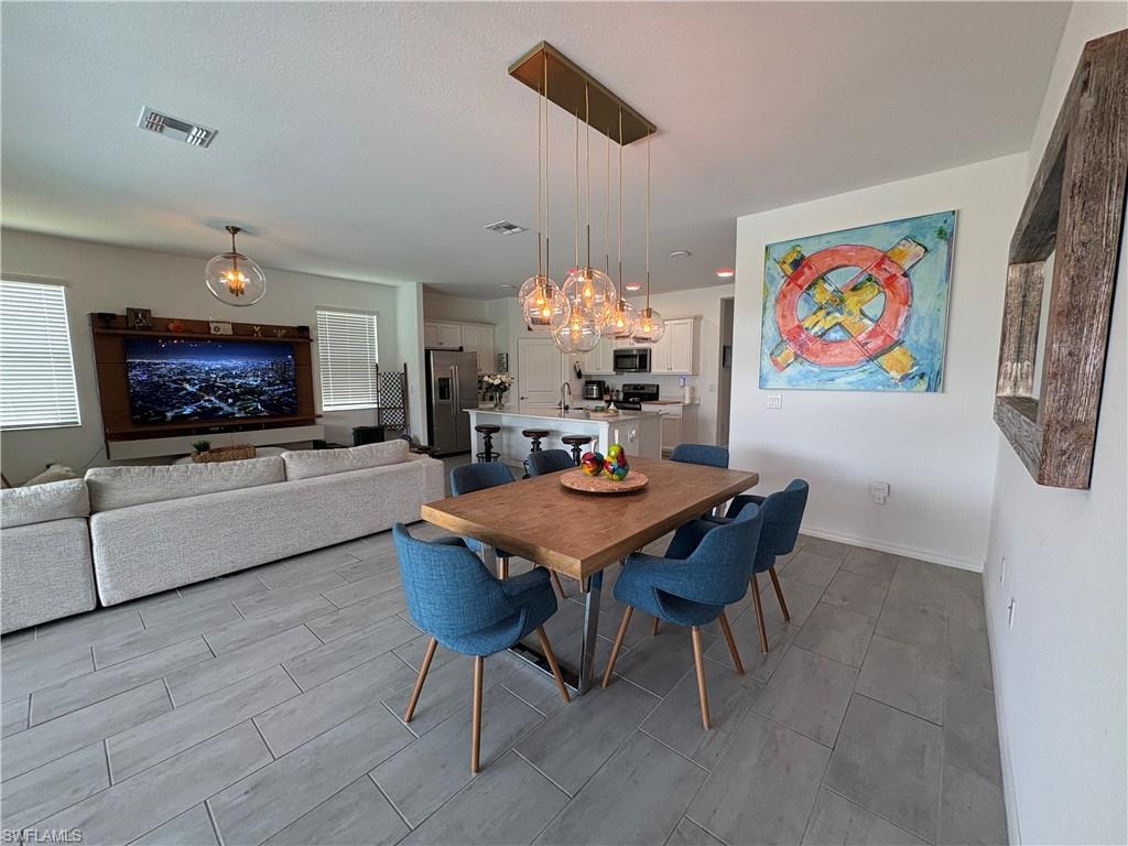 Open concept living area featuring wood-finish flooring, a linear pendant light fixture, recessed lighting, and white baseboards