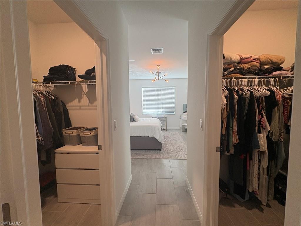 Hallway with tile flooring featuring two walk-in closets with wire shelving systems