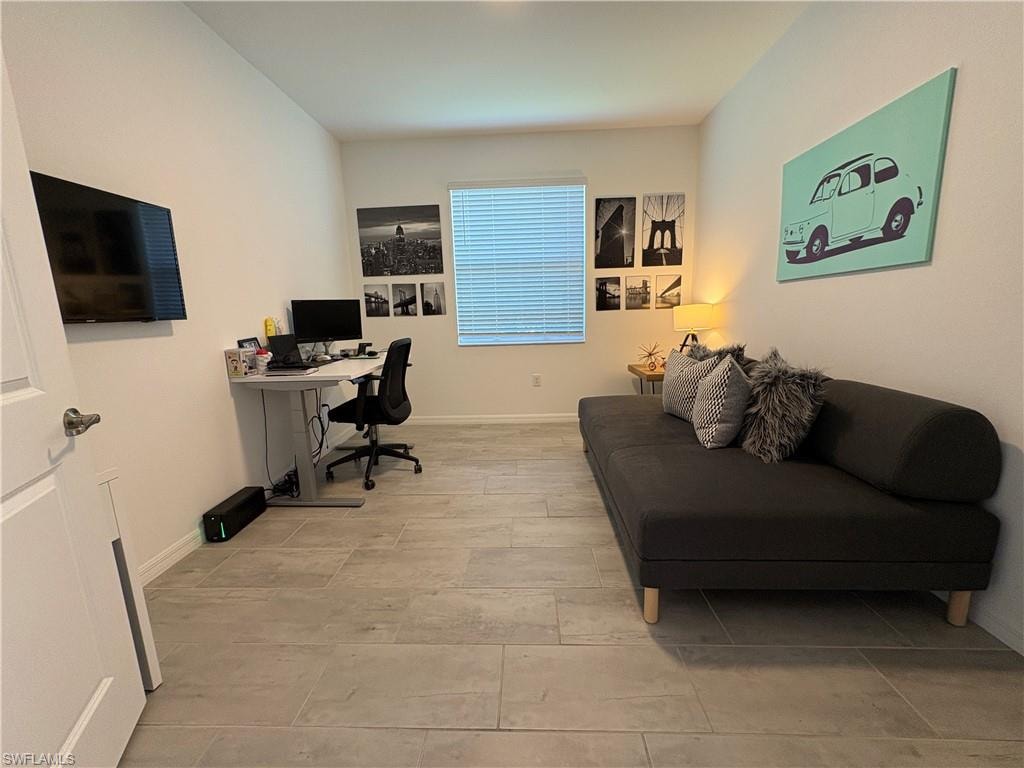 Spacious room featuring light-toned tile flooring, a single window with blinds, and white painted walls