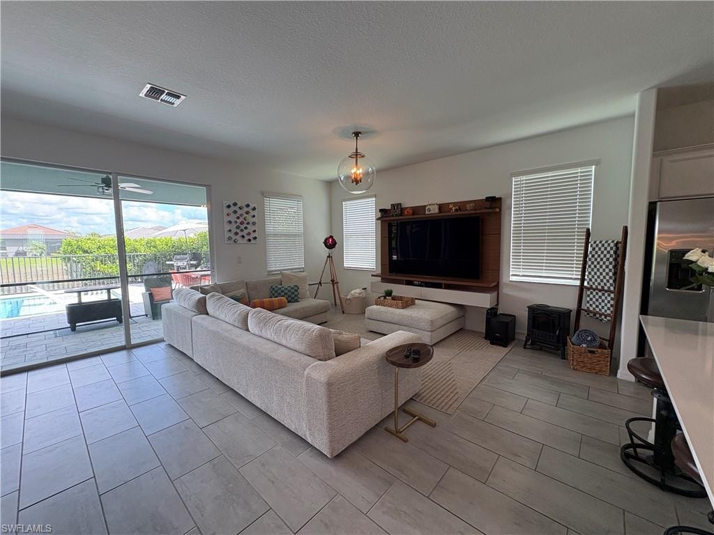 Spacious living area featuring large format tile flooring, a built-in media center, and sliding glass doors opening to a screened patio with a pool