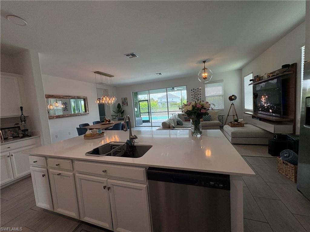 Spacious open-concept interior featuring a kitchen island with an undermount sink, white cabinetry, and stainless steel dishwasher