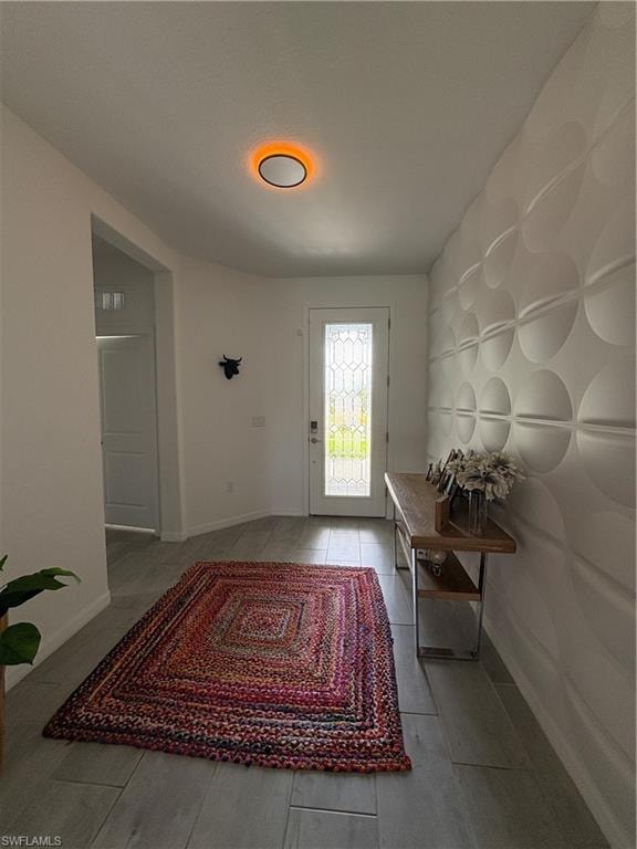 Entryway featuring a decorative front door with an integrated glass panel and sidelights, wood-finish flooring, and a textured accent wall