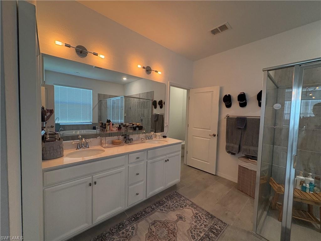 Dual vanity with white cabinetry, light-toned countertops, and brushed nickel fixtures