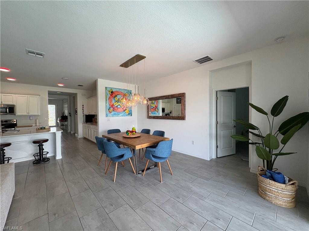 Open-concept dining area featuring a wood-finish table and a contemporary rectangular pendant light fixture
