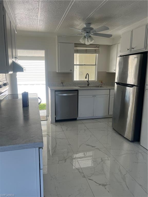 Kitchen with a ceiling fan, stainless steel dishwasher, a sink, decorative backsplash, and fridge