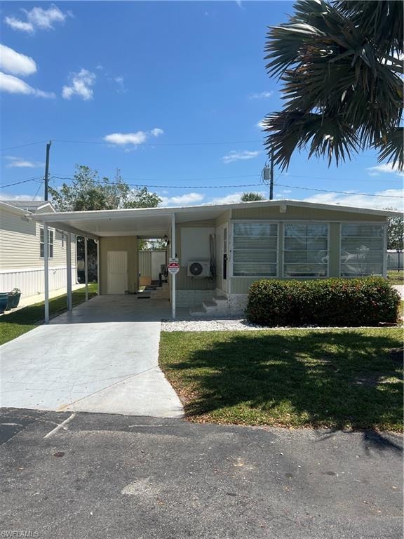 View of front facade featuring a front yard, concrete driveway, and an attached carport