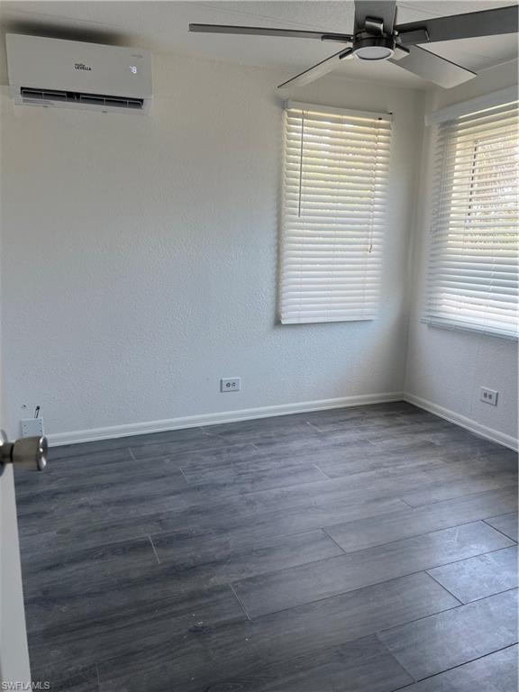 Empty room featuring baseboards, a ceiling fan, a wall unit AC, and dark wood-style flooring