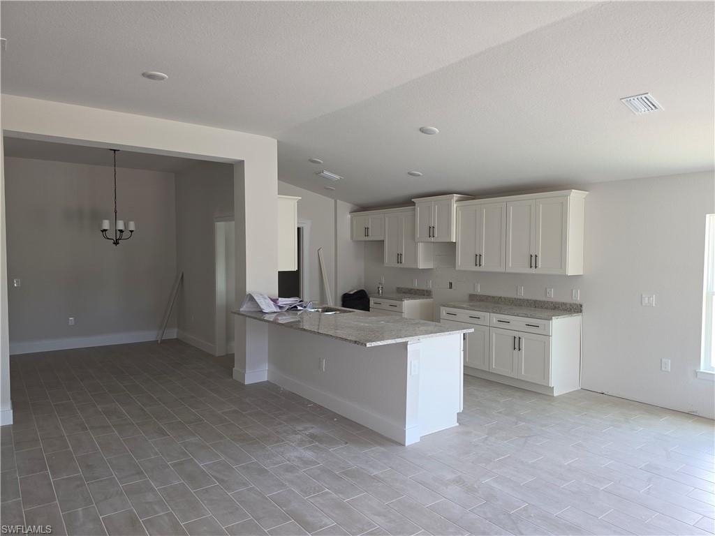 Open-concept kitchen featuring an island with a granite countertop, white shaker-style cabinetry, and recessed lighting