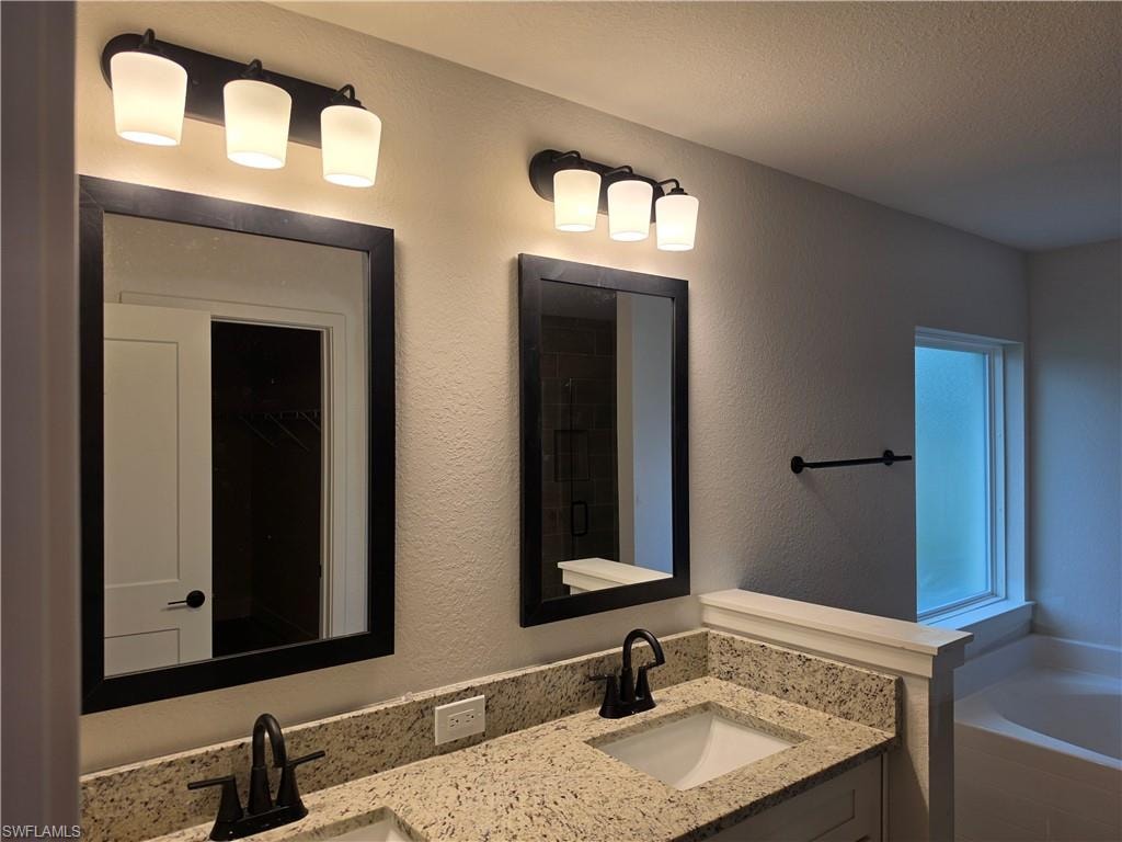 Double vanity featuring granite-look countertops, undermount sinks, and matte black fixtures