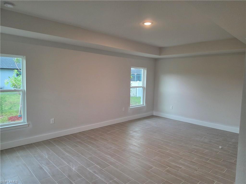 Spacious interior featuring a neutral color palette, tray ceiling with recessed lighting, and large windows