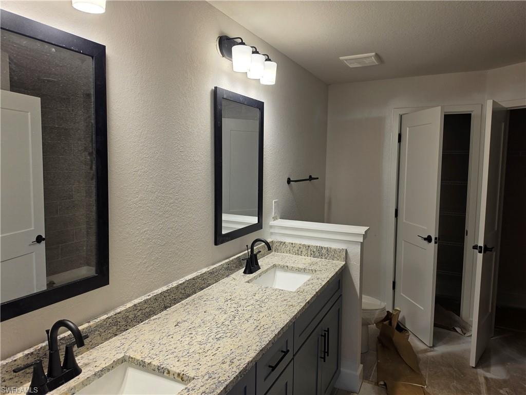 Dual vanity featuring granite-style countertops, matte black fixtures, and custom cabinetry