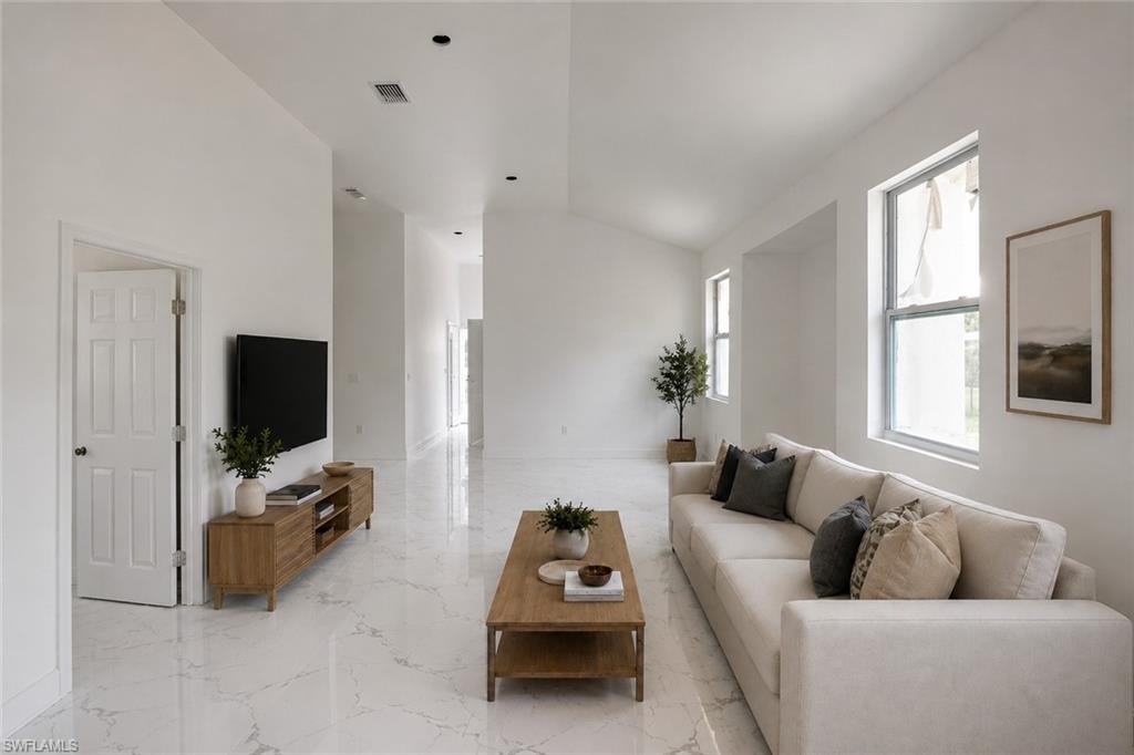 Open concept living area featuring white marble-look flooring, recessed lighting, vaulted ceilings, and multiple windows. Image digitally enhanced and virtually altered; actual property condition may differ. Image digitally enhanced and virtually altered; actual property condition may differ..