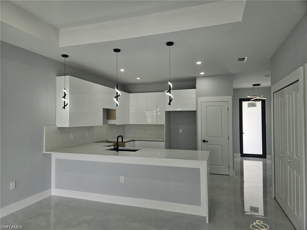 Kitchen with a sink, white cabinetry, modern cabinets, backsplash, and a peninsula
