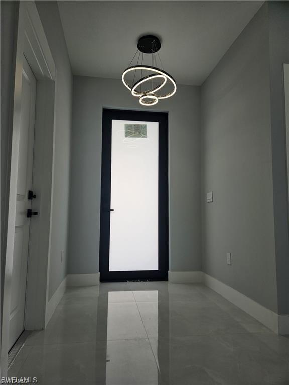 Unfurnished room with a chandelier and baseboards