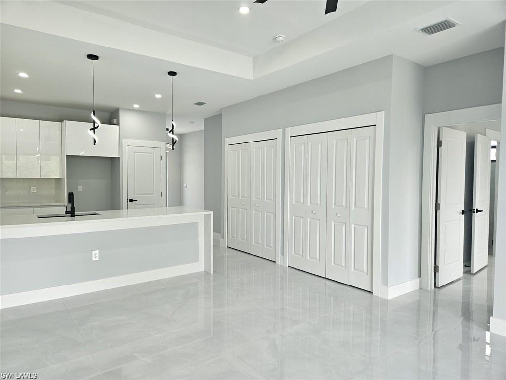 Kitchen with a sink, modern cabinets, white cabinets, recessed lighting, and light countertops
