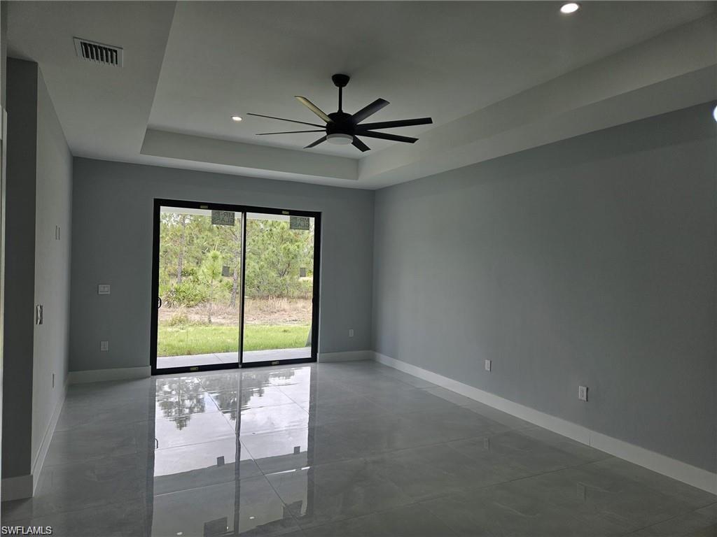 Empty room with a tray ceiling, baseboards, ceiling fan, recessed lighting, and concrete flooring