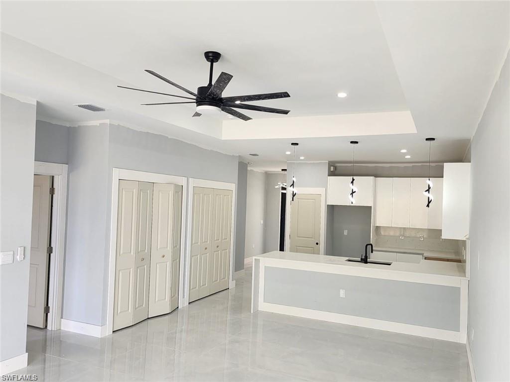 Unfurnished living room with a sink, baseboards, a ceiling fan, and recessed lighting