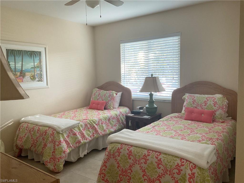 Guest bedroom with twin beds, ceiling fan, TV, tile flooring