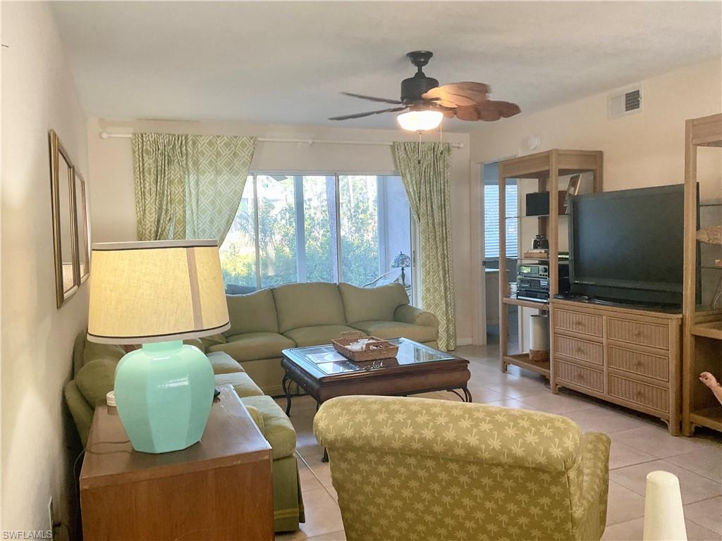 Tiled Living room with a ceiling fan and large TV