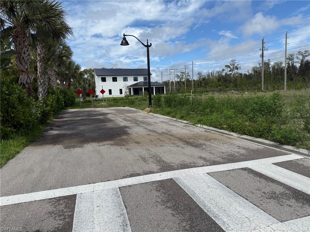 Asphalt driveway leading to a two-story residence with a dark roof and white exterior