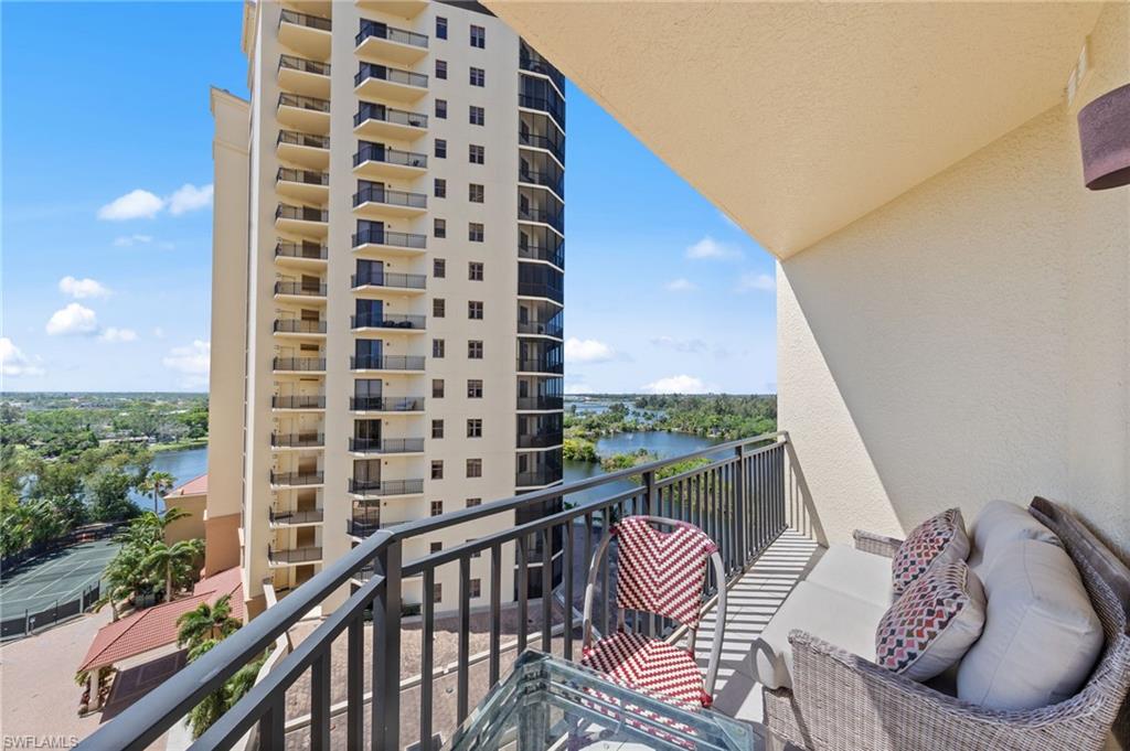 The property features a private balcony with a metal railing, offering expansive views of a body of water and distant buildings