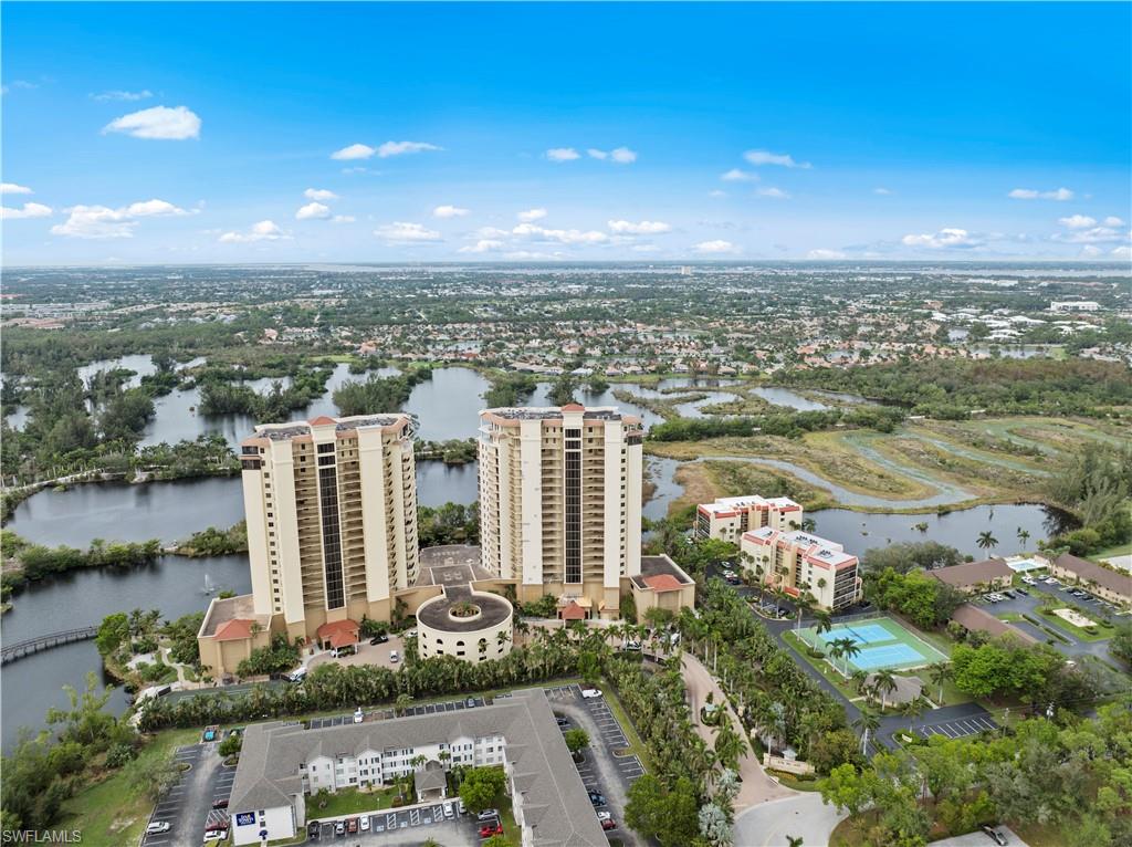 Aerial view showcasing two high-rise buildings, surrounded by water features and lush greenery