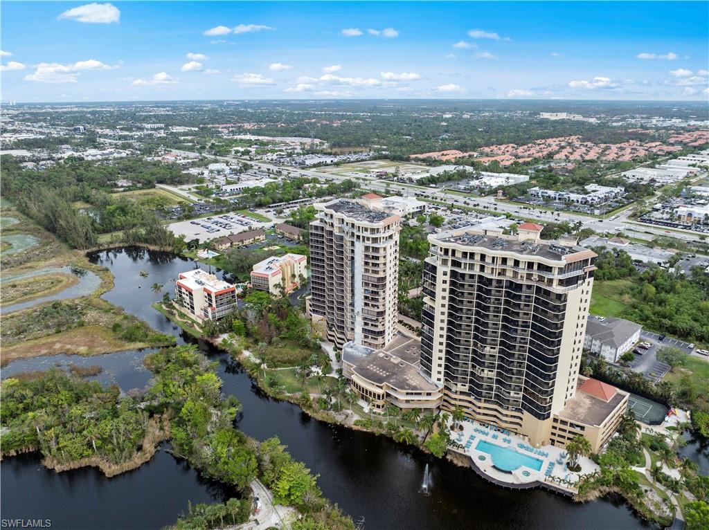 Aerial view of the property and its surrounding area, featuring a body of water, lush greenery, and a swimming pool