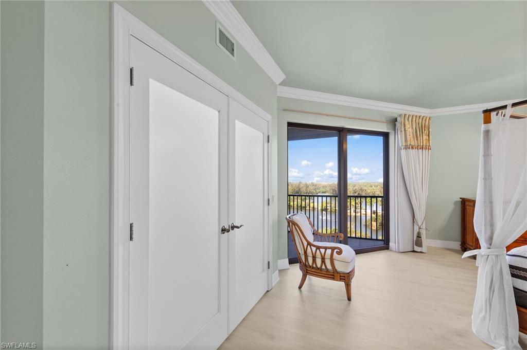 This room features light-colored flooring, direct access to a balcony with a water view, and crown molding