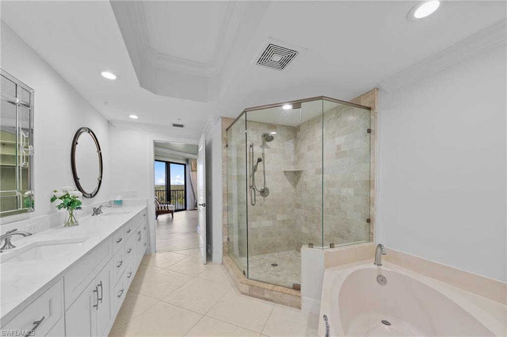 This bathroom features a double vanity with ample storage, a glass-enclosed shower with tile surround, and a built-in bathtub