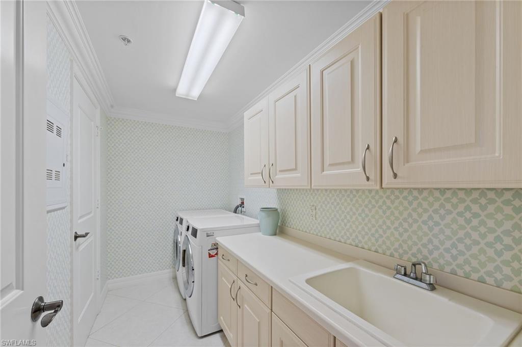 The laundry room features a utility sink, upper and lower cabinetry, and a countertop