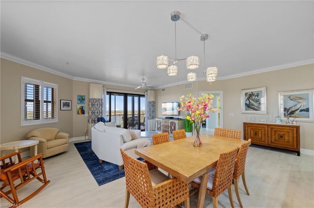 This spacious open-concept living area features light-toned flooring, crown molding, and a modern chandelier