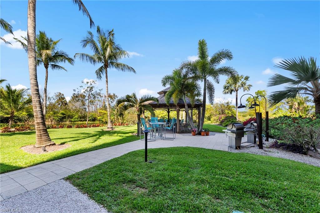 The property features a well-maintained lawn, mature palm trees, a paved patio area, and a gazebo with outdoor seating