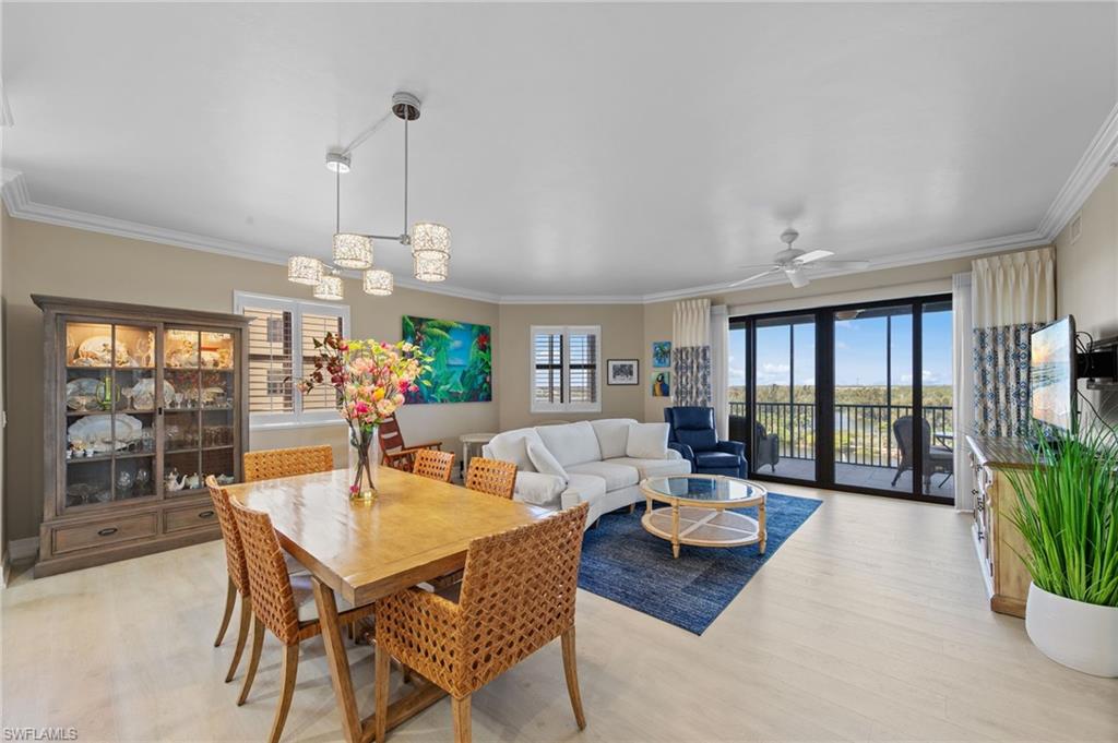 This open-concept living area features light-toned flooring, a dining space with a rectangular wooden table, and a living area with a large sofa